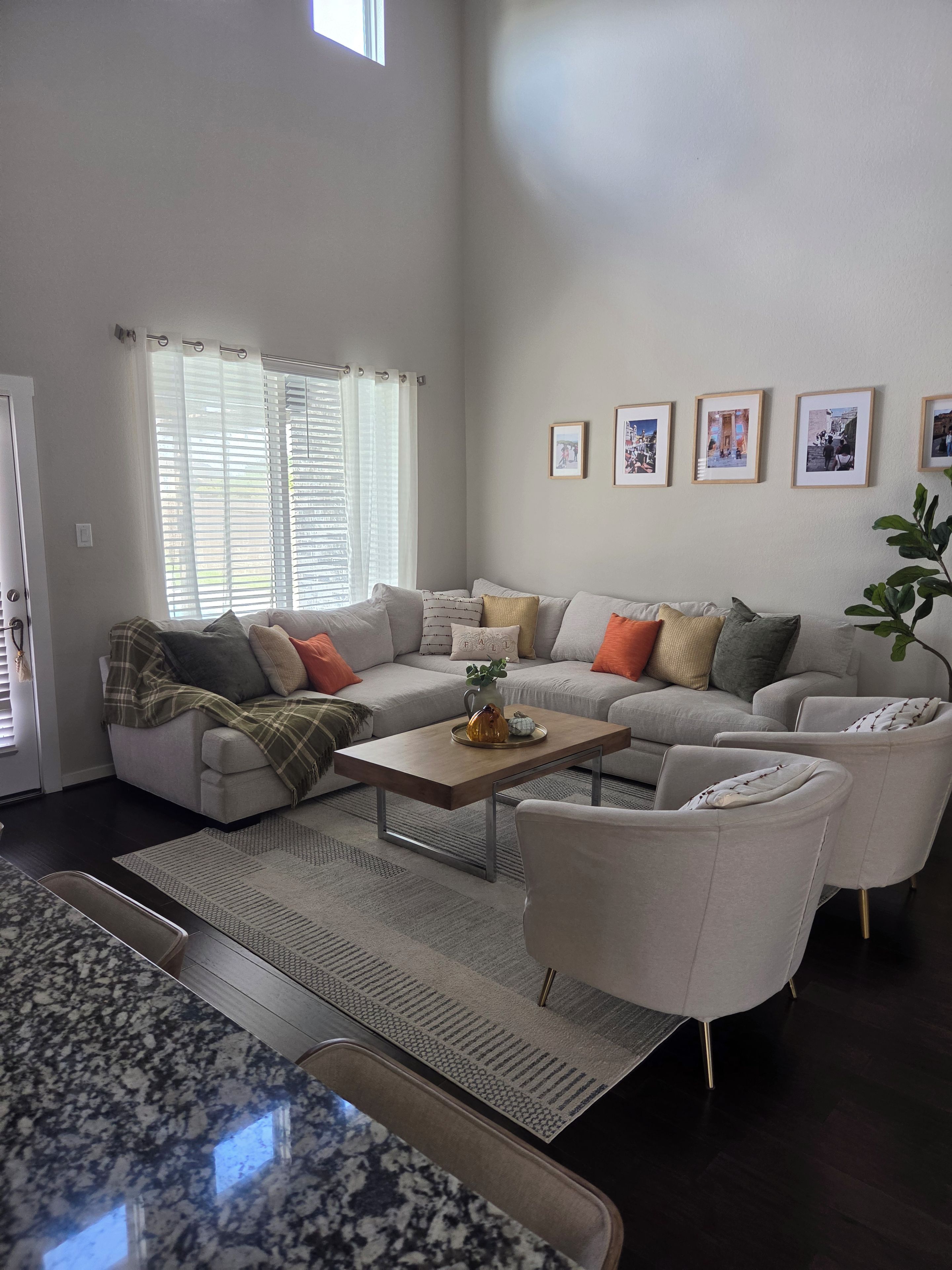 A modern living room with a sectional sofa, a coffee table, and a large window with blinds.