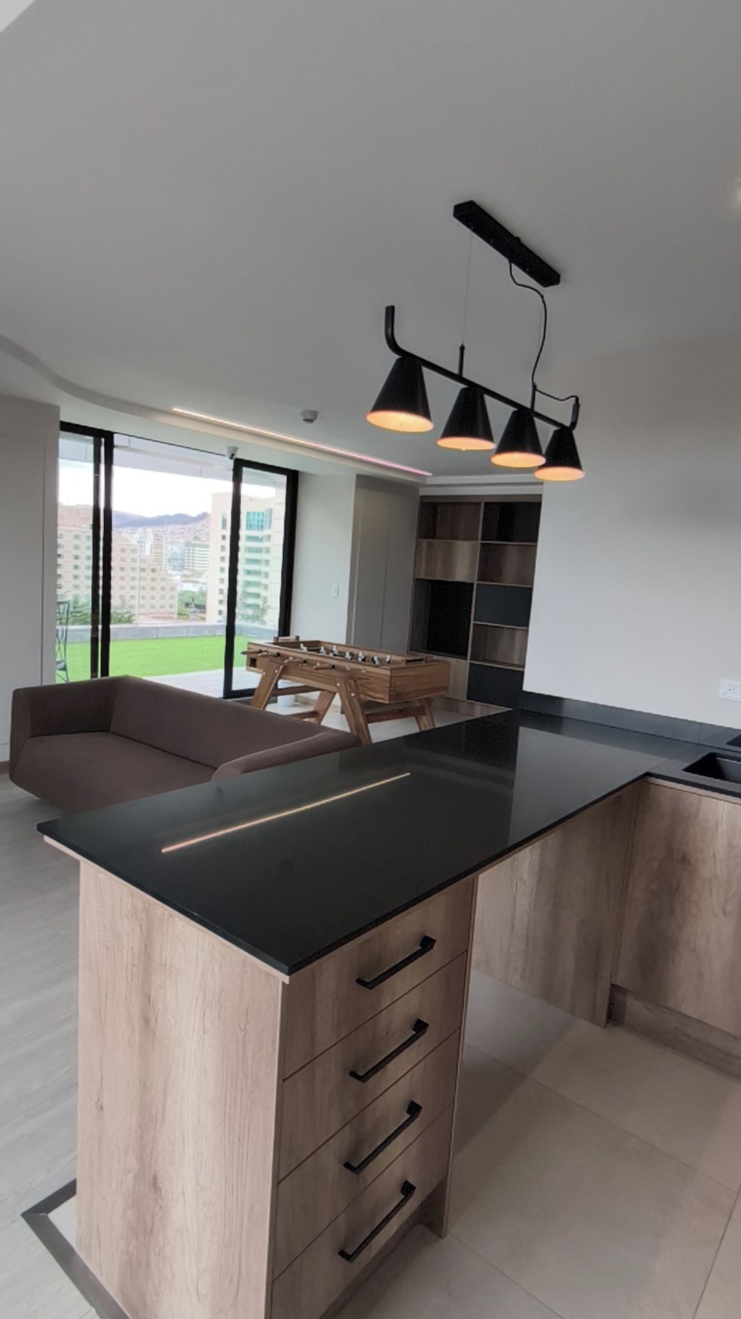 A modern kitchen with a central island, wooden cabinetry, and a built-in stove.
