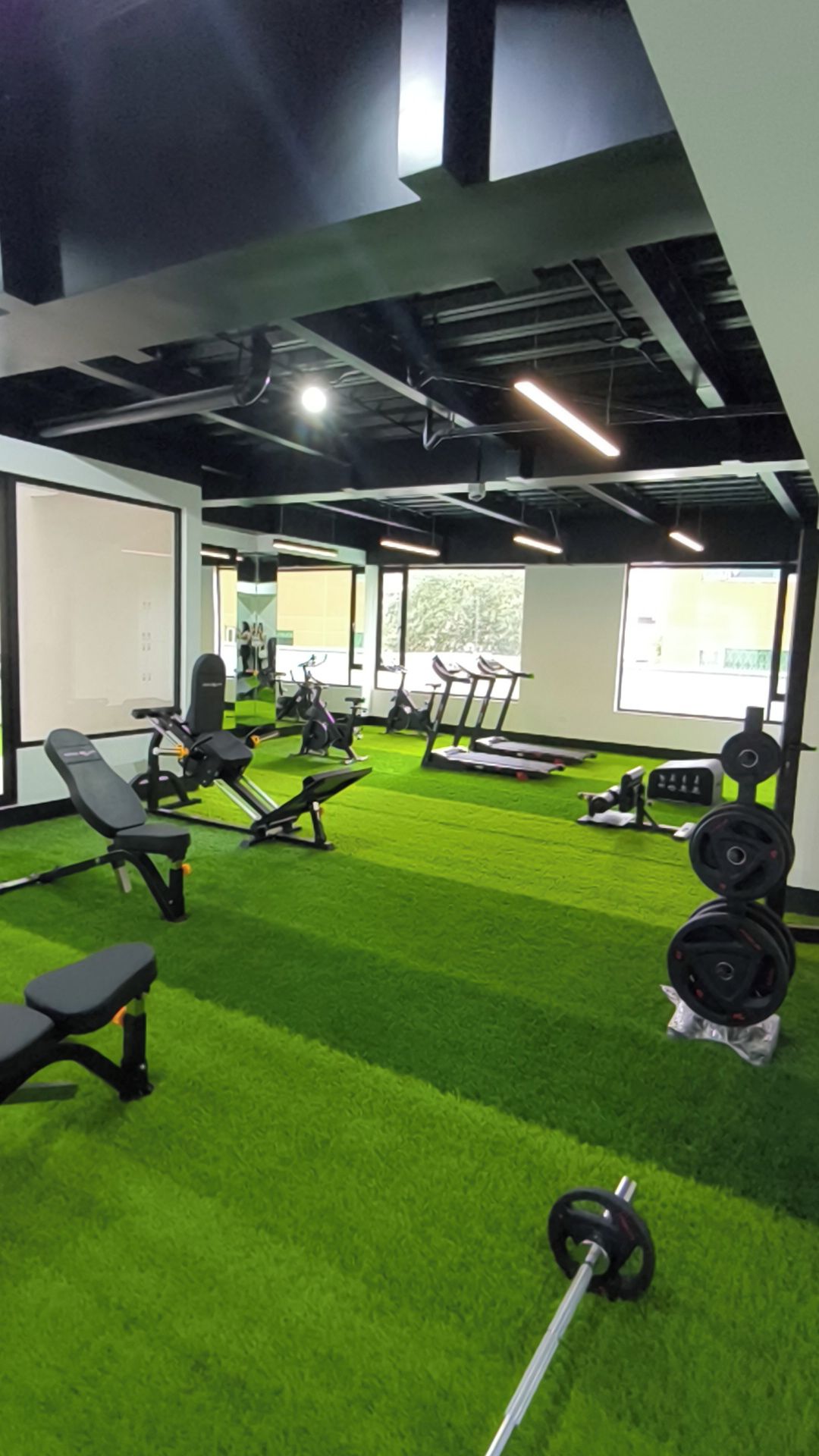 A gym with exercise equipment, green artificial turf, and a whiteboard.