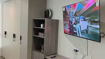 En moderne stue med et fladskærms-tv på væggen, et træunderholdningsmøbel og indbyggede hylder.