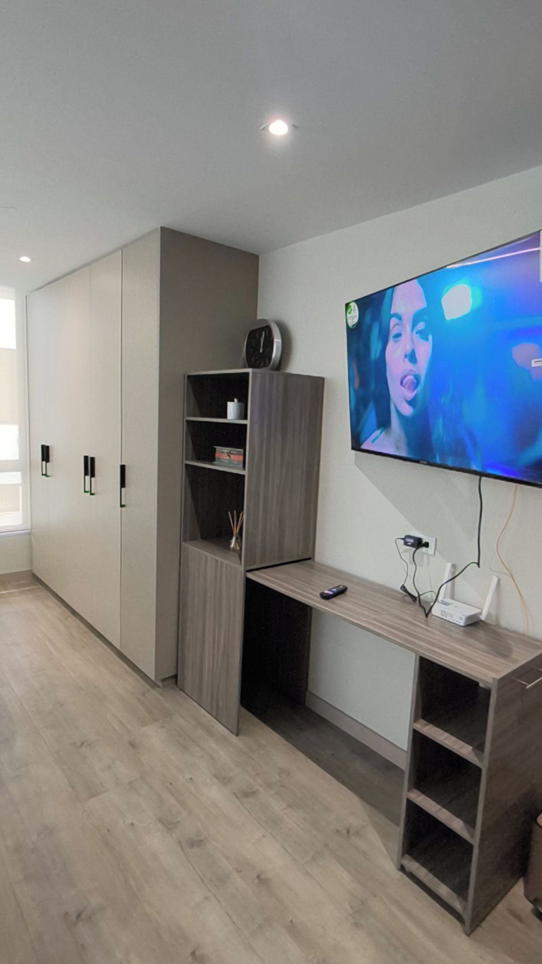 A modern room with a built-in TV, a desk, and a wardrobe.