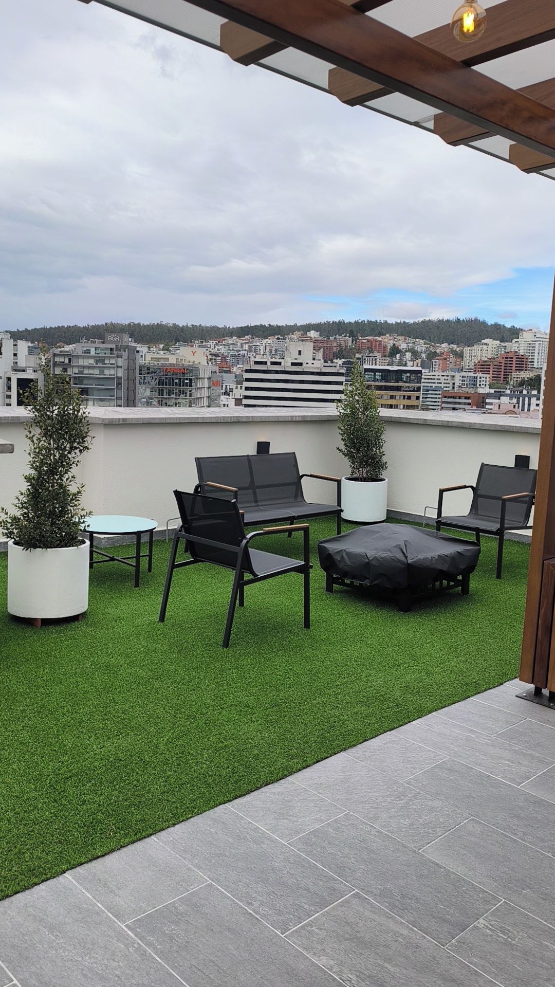 Une terrasse sur le toit, dotée d’un revêtement d’herbe artificielle, de mobilier d’extérieur et offrant une vue sur le paysage urbain.