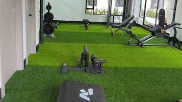 Een sportschool met kunstgras, trainingsapparatuur en grote ramen.