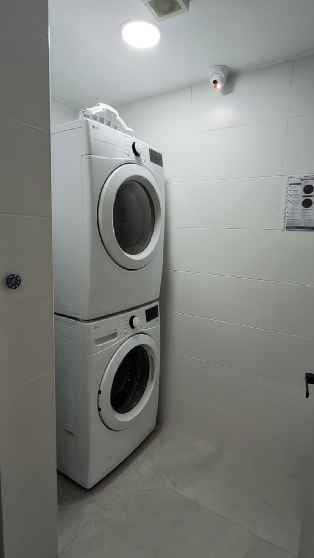 A laundry area with two stacked washing machines and a ceiling light.