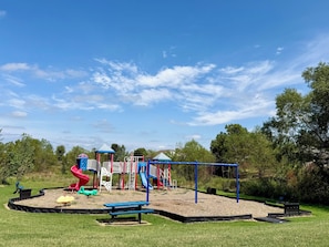 A playground with a slide, climbing structures, and a picnic table. - Experience Route 66! Stay in this unique 3BR themed home featuring Chicago, Springfield, & Los Angeles-inspired bedrooms and a Tulsa-themed living room, a fenced yard, and private patio. (Broken Arrow)