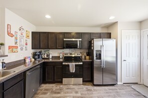 Une cuisine moderne avec des meubles de couleur sombre, des appareils électroménagers en acier inoxydable et un plan de travail en granit.
