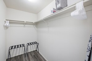 Une petite pièce aux murs blancs, avec un sol gris, un plafond blanc et une étagère blanche fixée au plafond, sur laquelle se trouve une boîte étiquetée « BLACK+DECKER EASY STEAMER ».