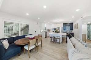 A modern kitchen with white cabinetry, a central island, and a dining area with a wooden table and chairs. - BG Beach Club 3B - 2 bed / 2 bath / Close to VIllage / Sleeps 6 / No Stairs! (Boca Grande)