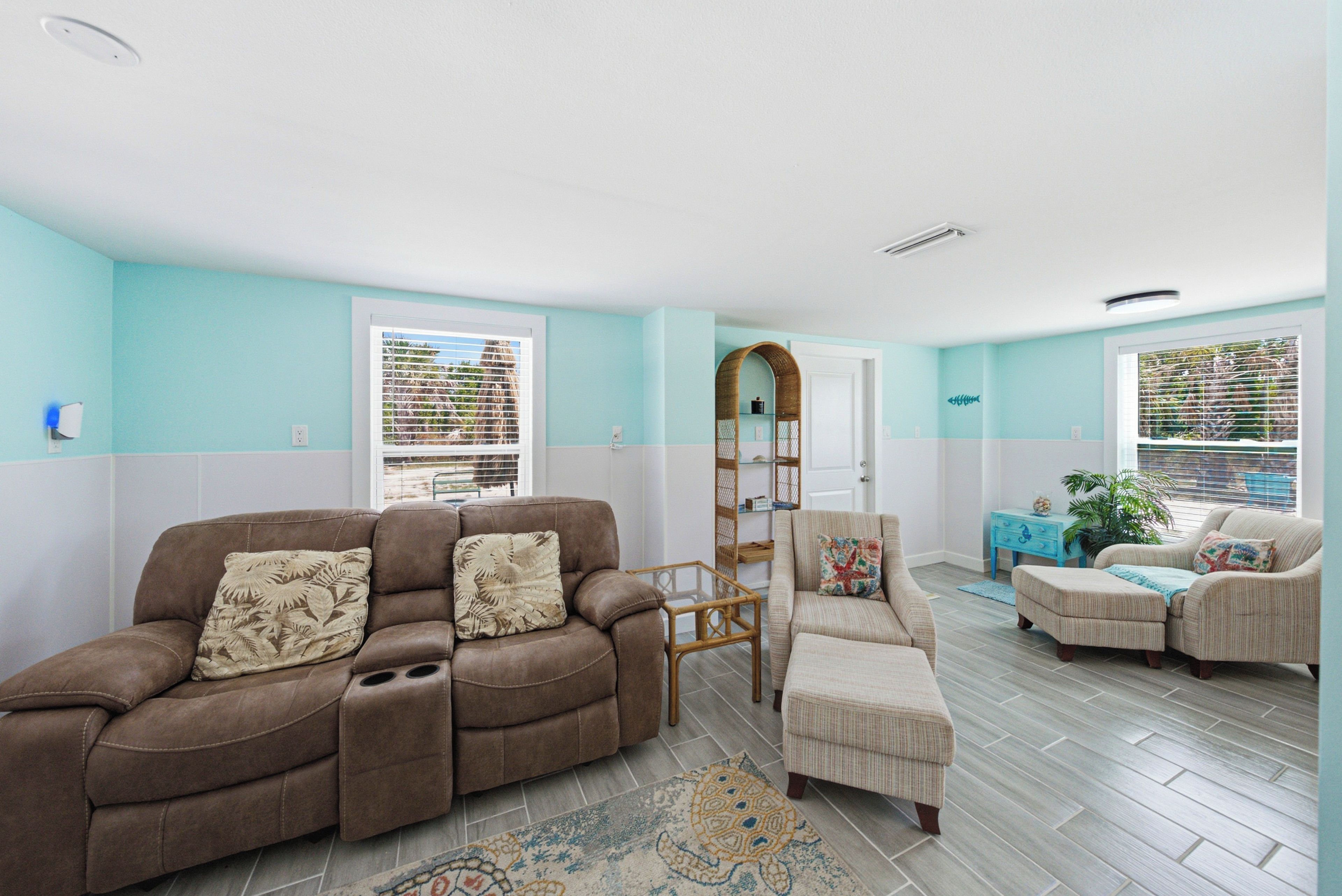 A living room with a brown sofa, a patterned armchair, and a blue side table with a plant.