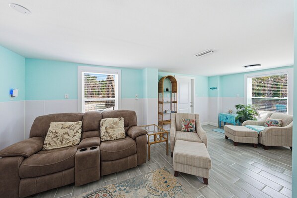 A living room with a brown sofa, a patterned armchair, and a blue side table with a plant.