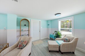 Una habitación con dos sillones, una mesita, un espejo y una ventana con persianas.