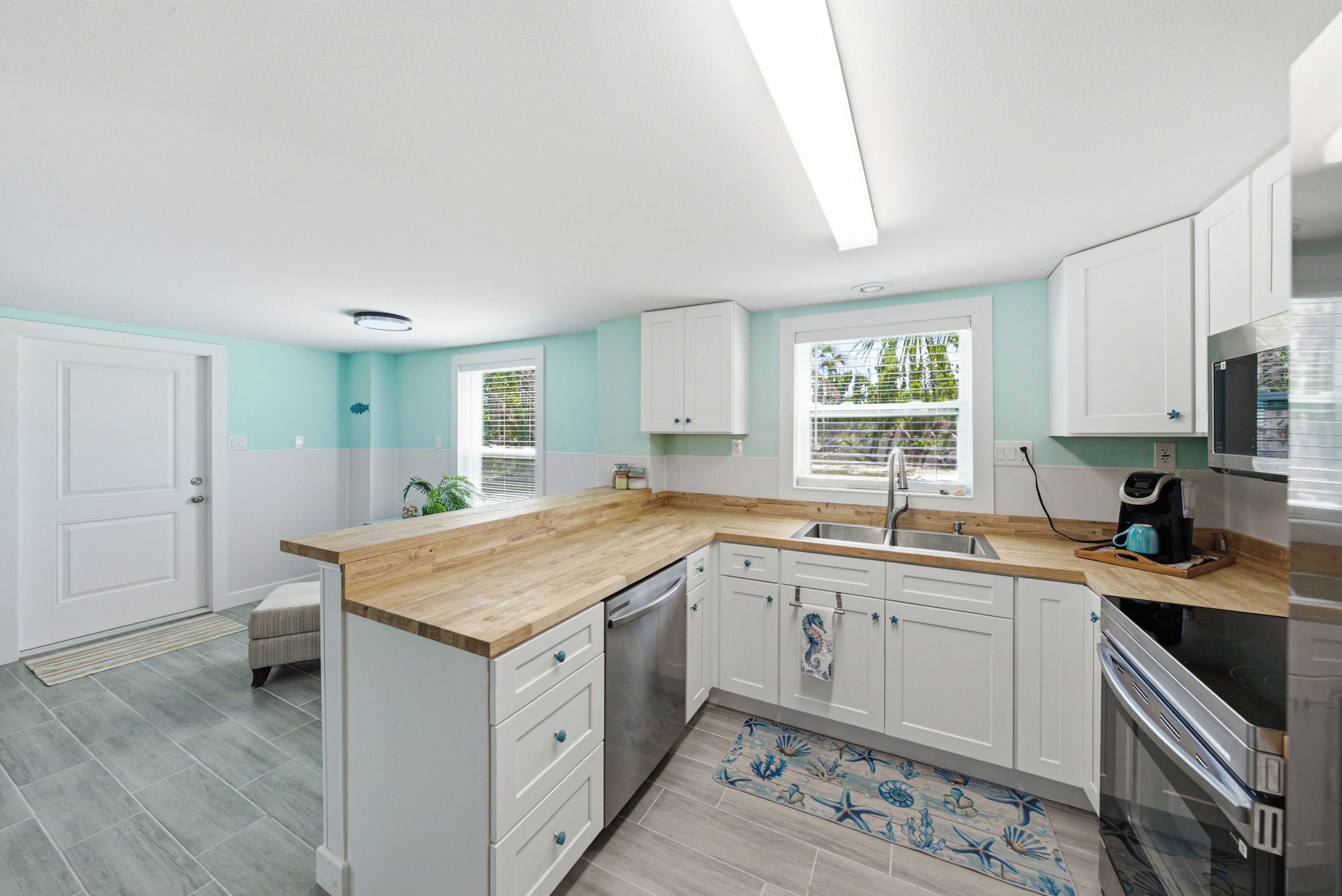 A modern kitchen with white cabinetry, a wooden countertop, and a stainless steel refrigerator.