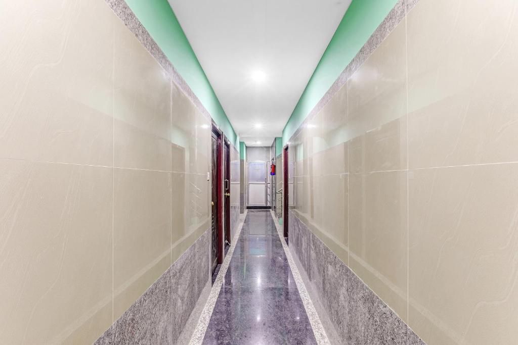 A corridor with a marble floor and green accent walls, leading to a door at the end.