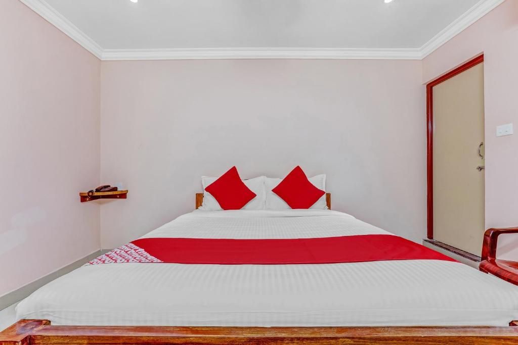 Un lit simple avec un cadre en bois, une couvre-lit rouge et blanche et deux oreillers rouges.