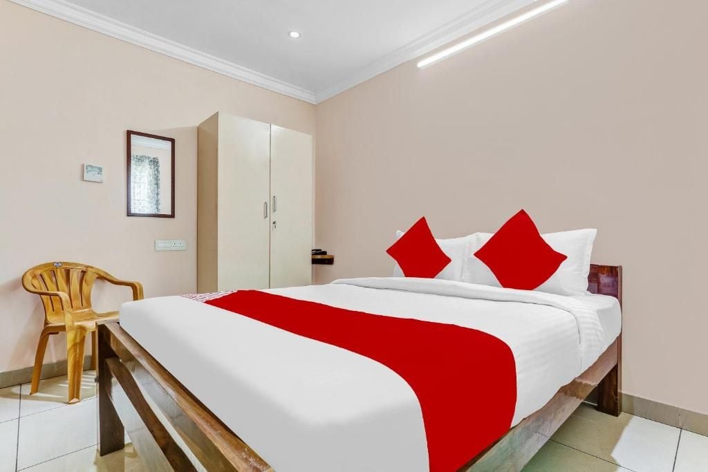A hotel room with a bed, a wooden chair, a wardrobe, and a framed picture on the wall.