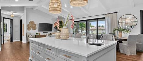 A modern kitchen with a central island, white cabinetry, and a large window.