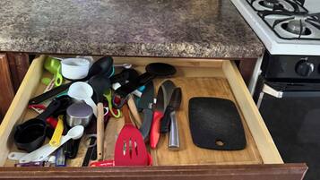 Un cajón de cocina con diferentes utensilios y utensilios de cocina.