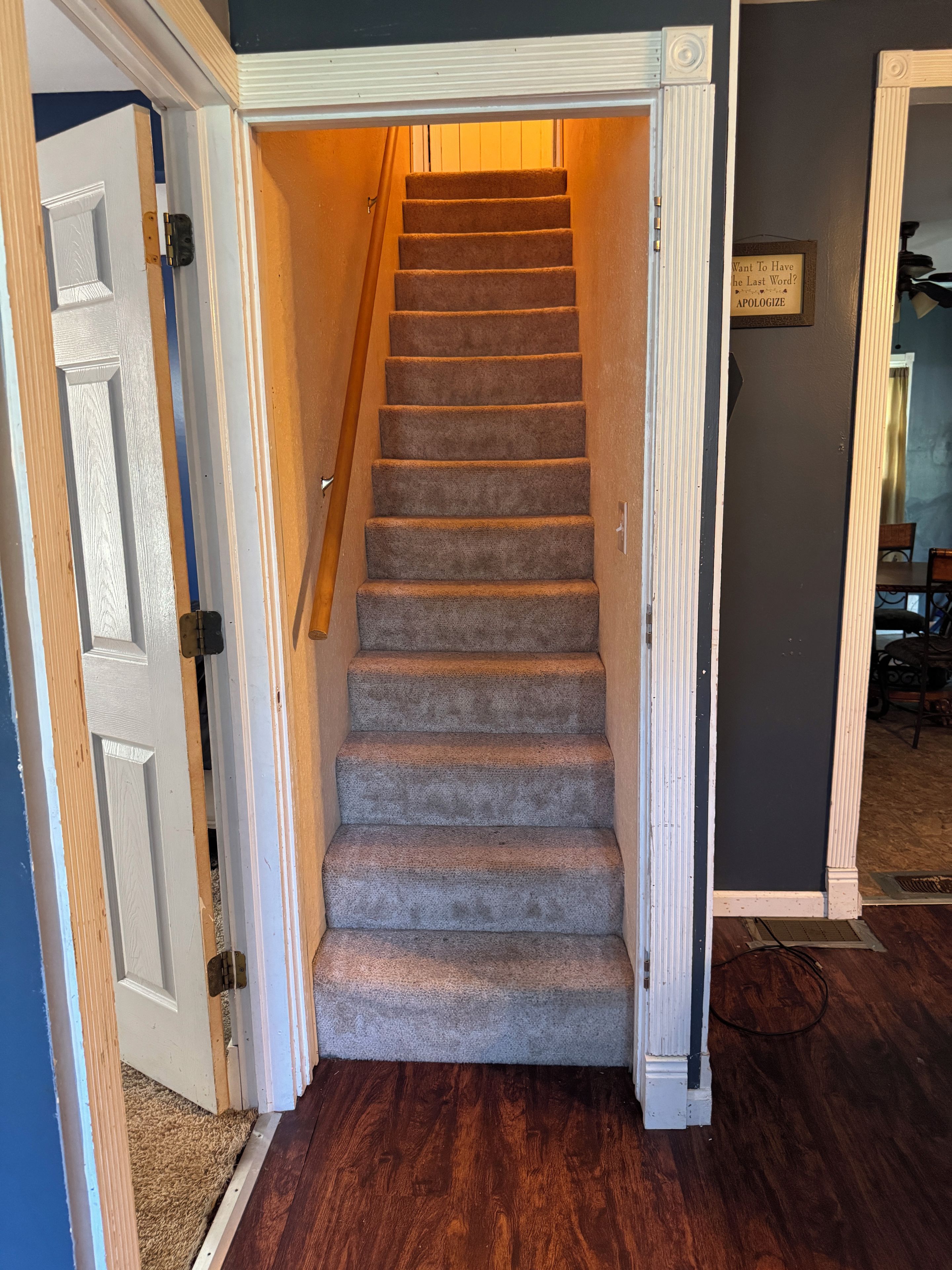 A carpeted staircase with a wooden handrail leading to a landing.