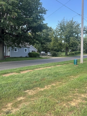 A residential street with houses, a grassy area, and a clear sky.
