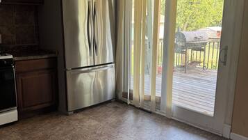 Una cocina con un refrigerador de acero inoxidable, un ventilador de techo y un patio con puerta corrediza de vidrio.