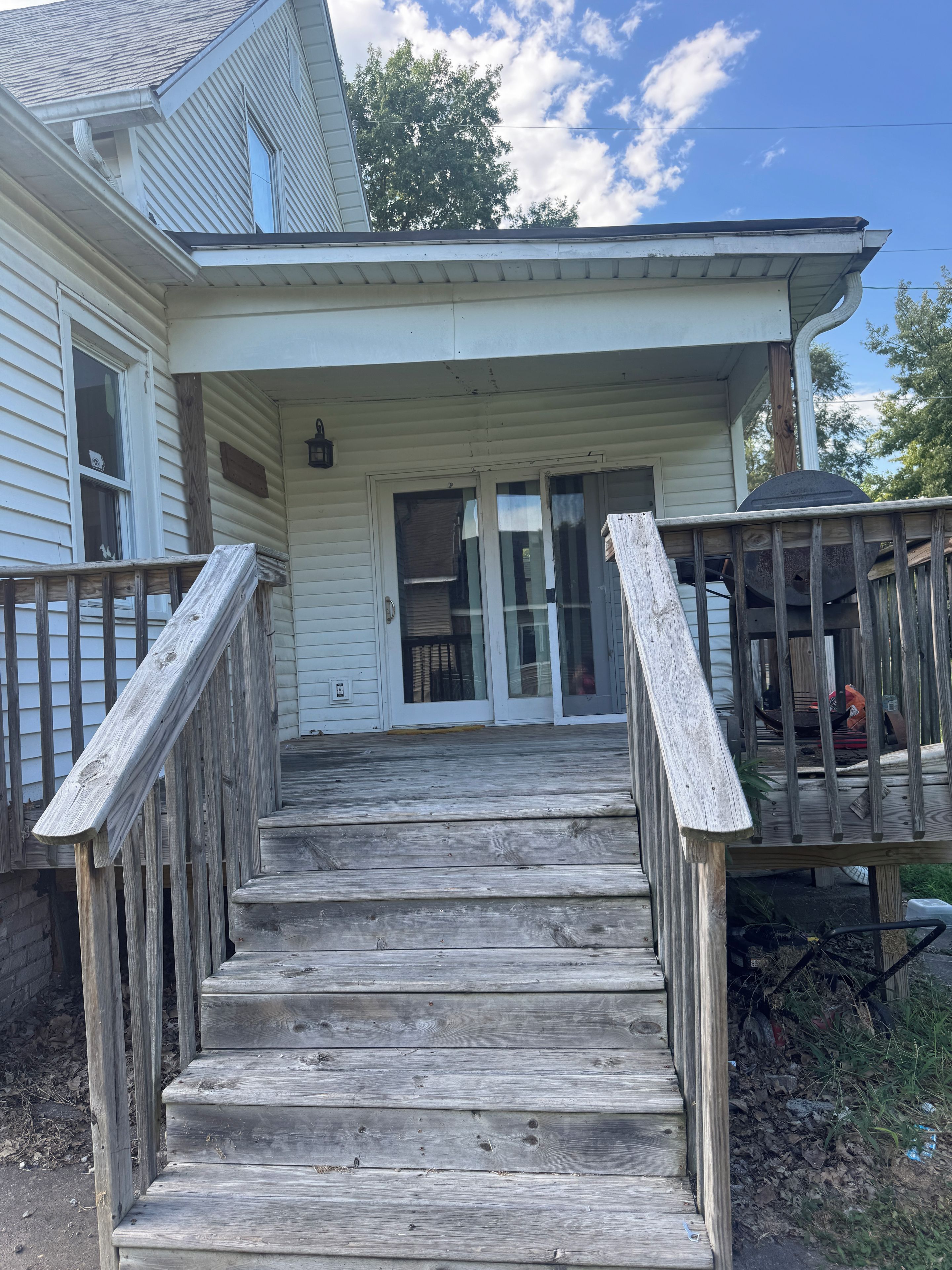 A wooden staircase leading to a house's front door with a covered porch area.