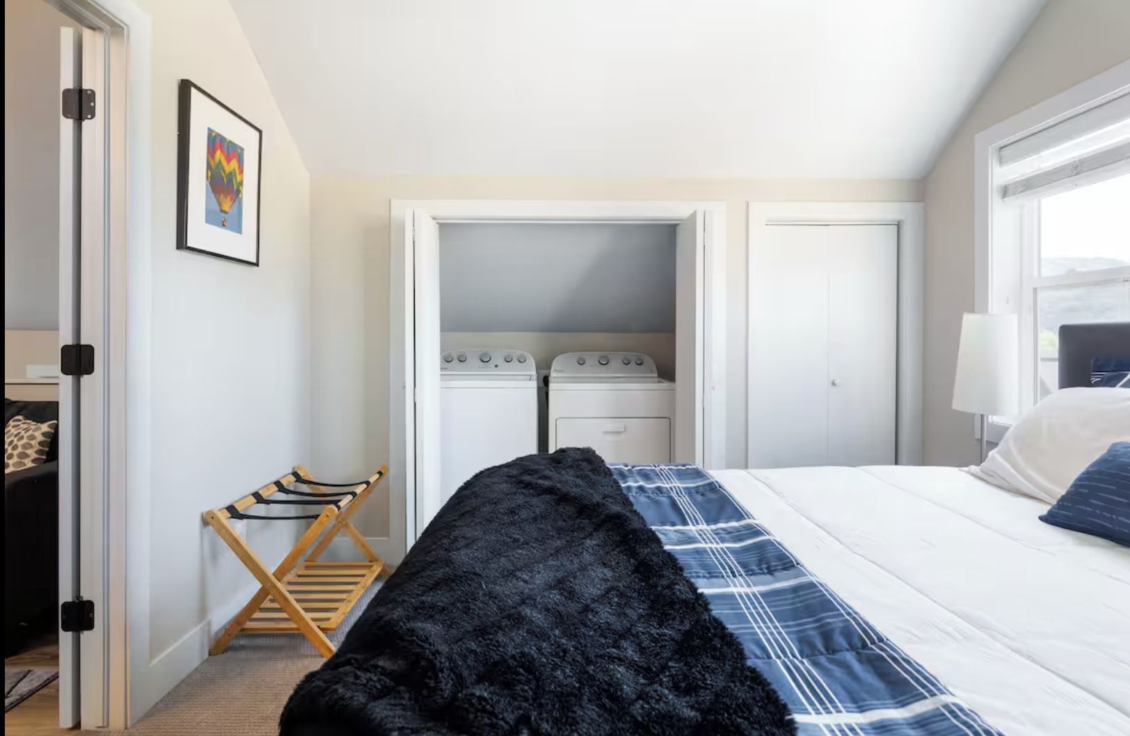 A hotel room with a bed, a wardrobe, a drying rack, and a window.
