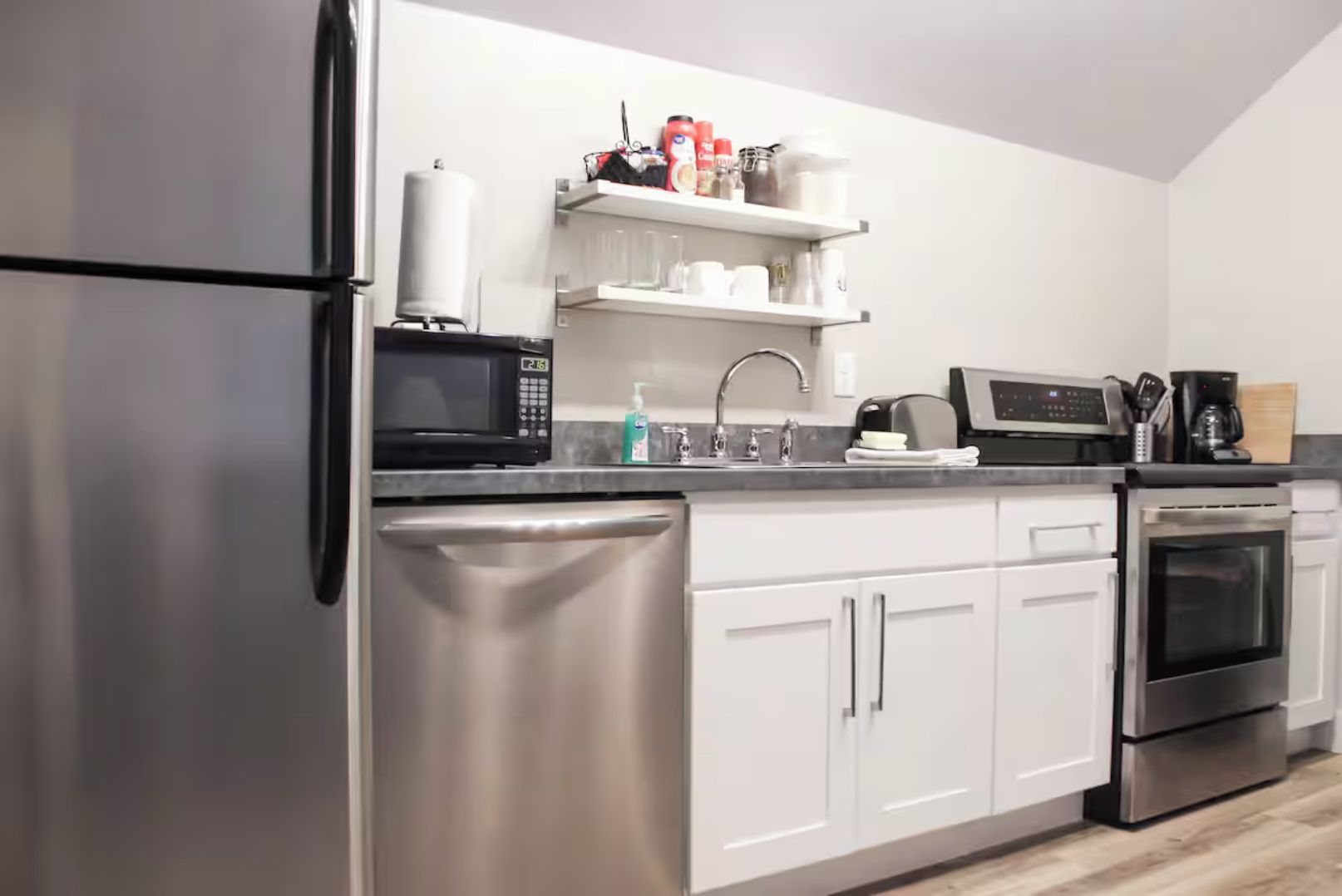 A modern kitchen with stainless steel appliances, white cabinetry, and a built-in oven.