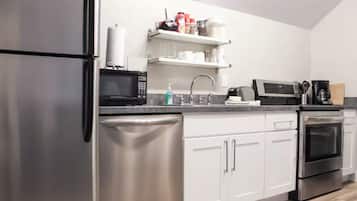 A modern kitchen with stainless steel appliances, white cabinetry, and a built-in oven.