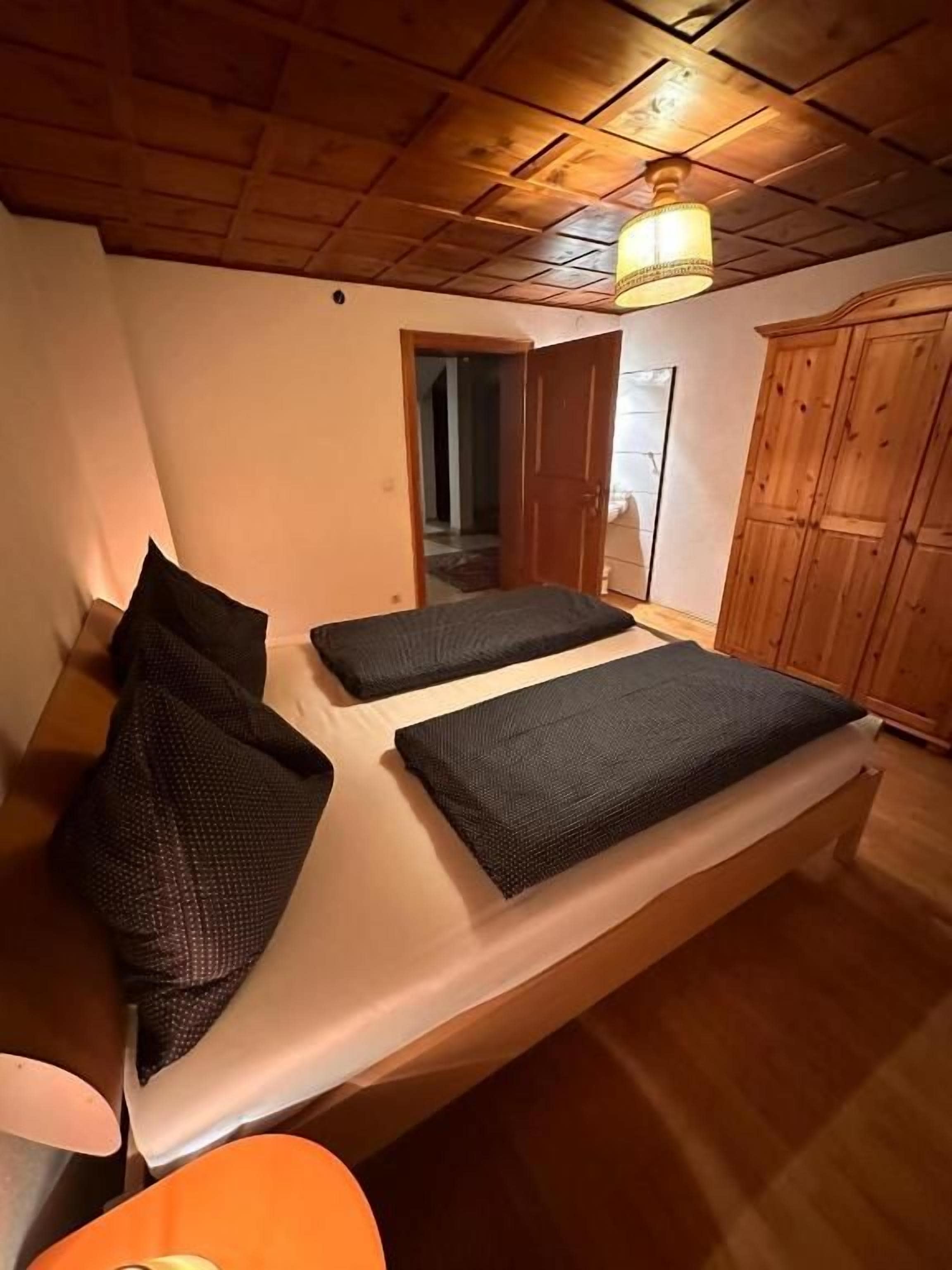 Ein Zimmer mit einem Bett, einem Kleiderschrank und einer Tür zu einem weiteren Raum.
