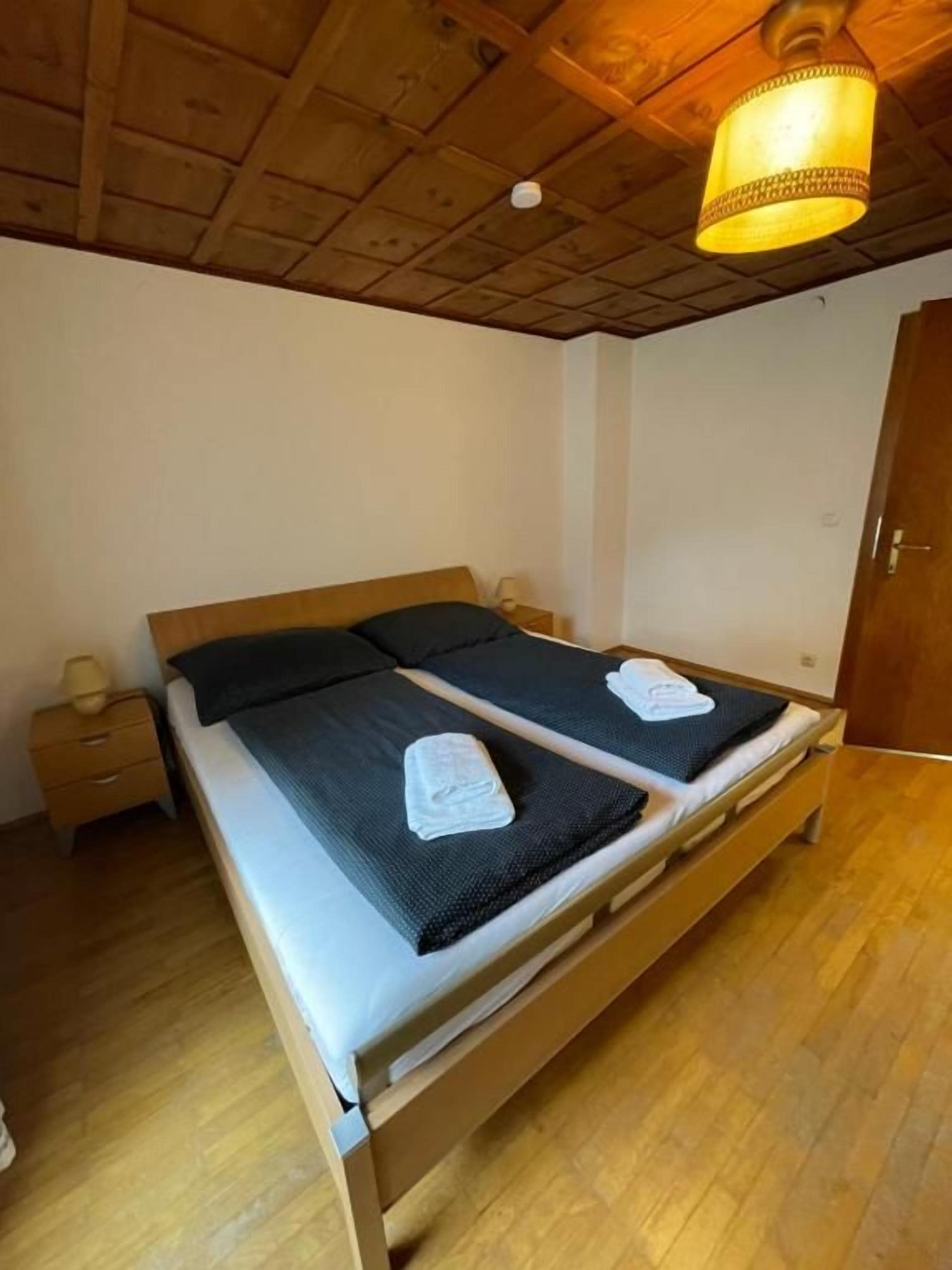 Una cama doble con cabecera de madera, una mesita de noche y una lámpara colgante.