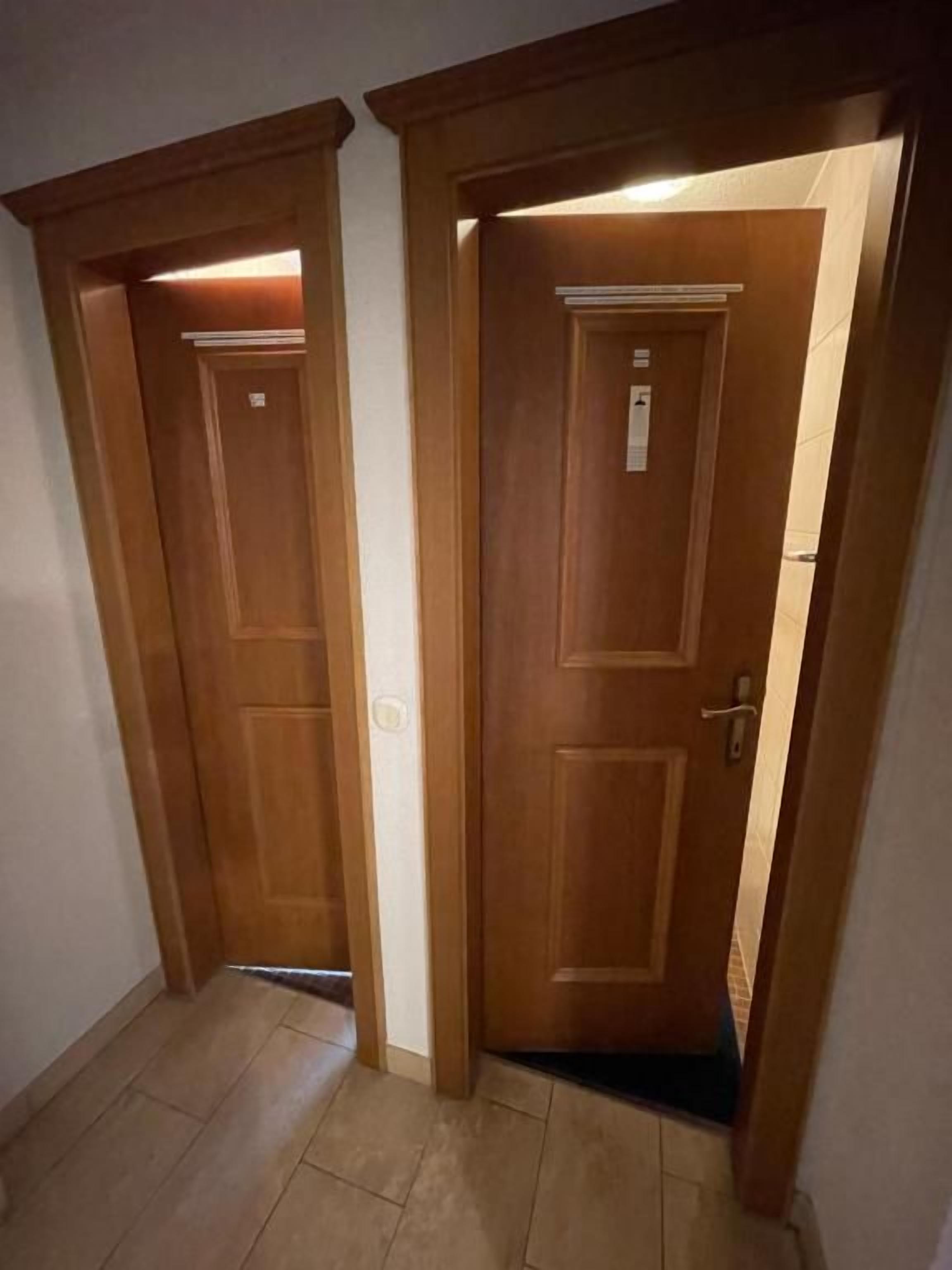 A hallway with two wooden doors, one of which is slightly ajar.
