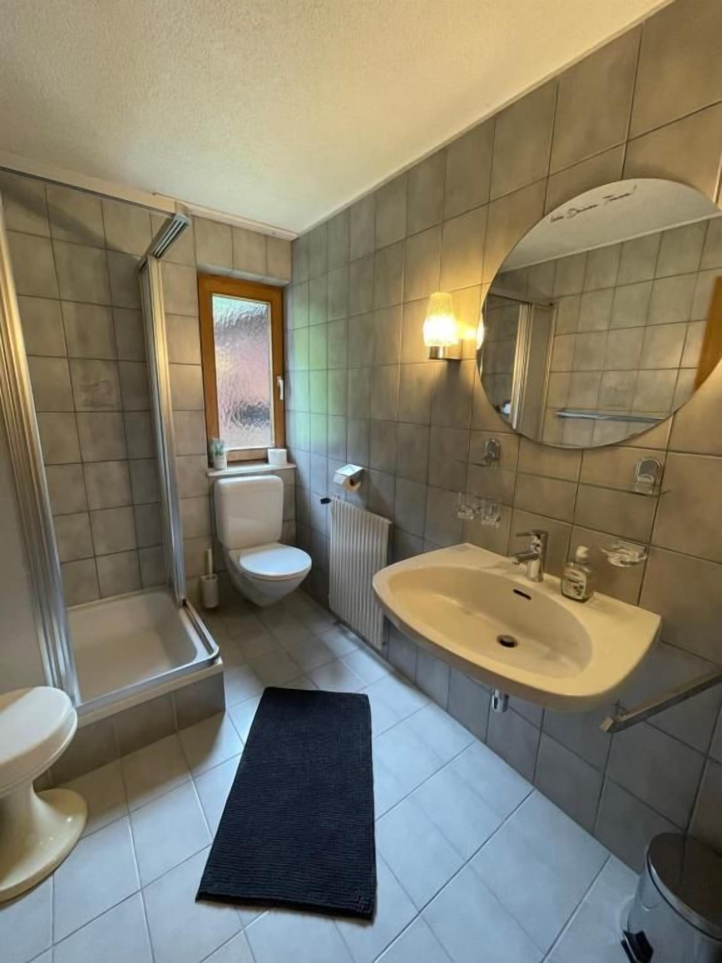 A bathroom with a toilet, sink, and shower.