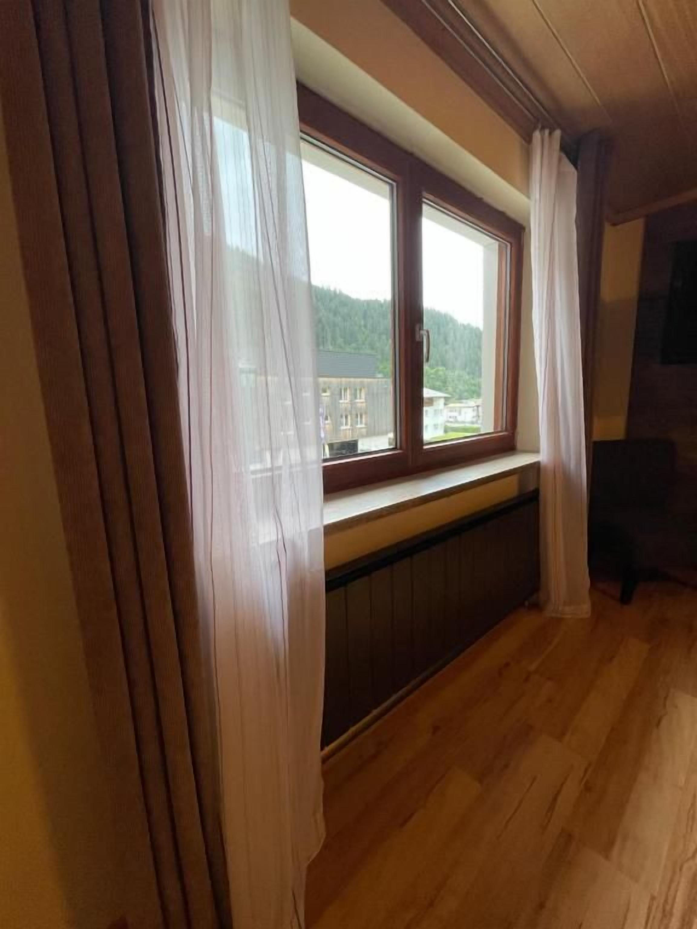 Una habitación con un ventanal grande, suelo de madera y un radiador debajo de la ventana.