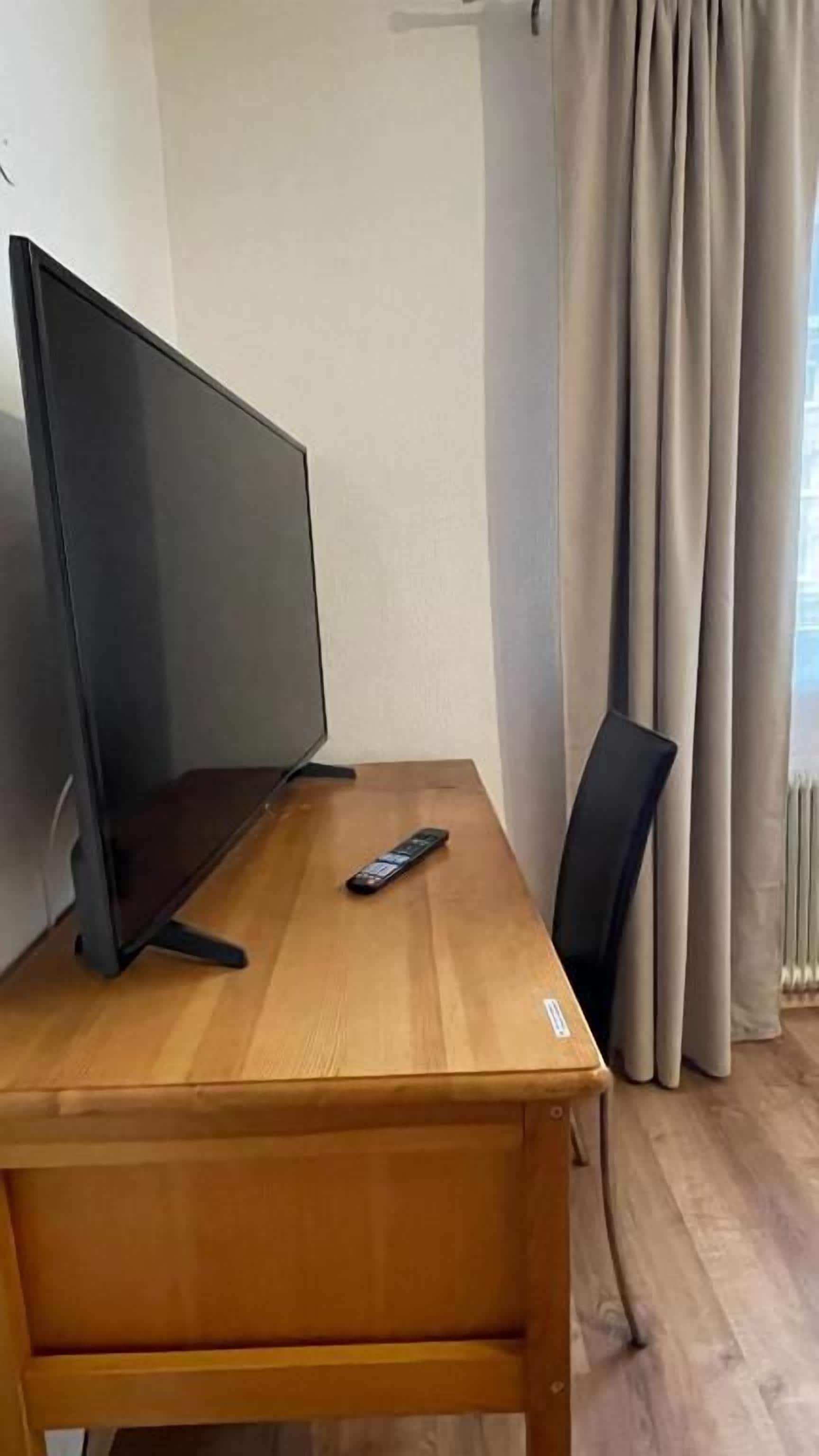 Ein Holztisch mit einem Flachbildfernseher und einer Fernbedienung.