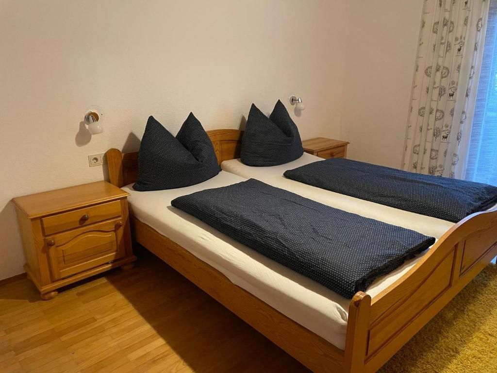 Ein Doppelbett mit Holzrahmen, zwei Nachttische und ein gemustertes Vorhang.