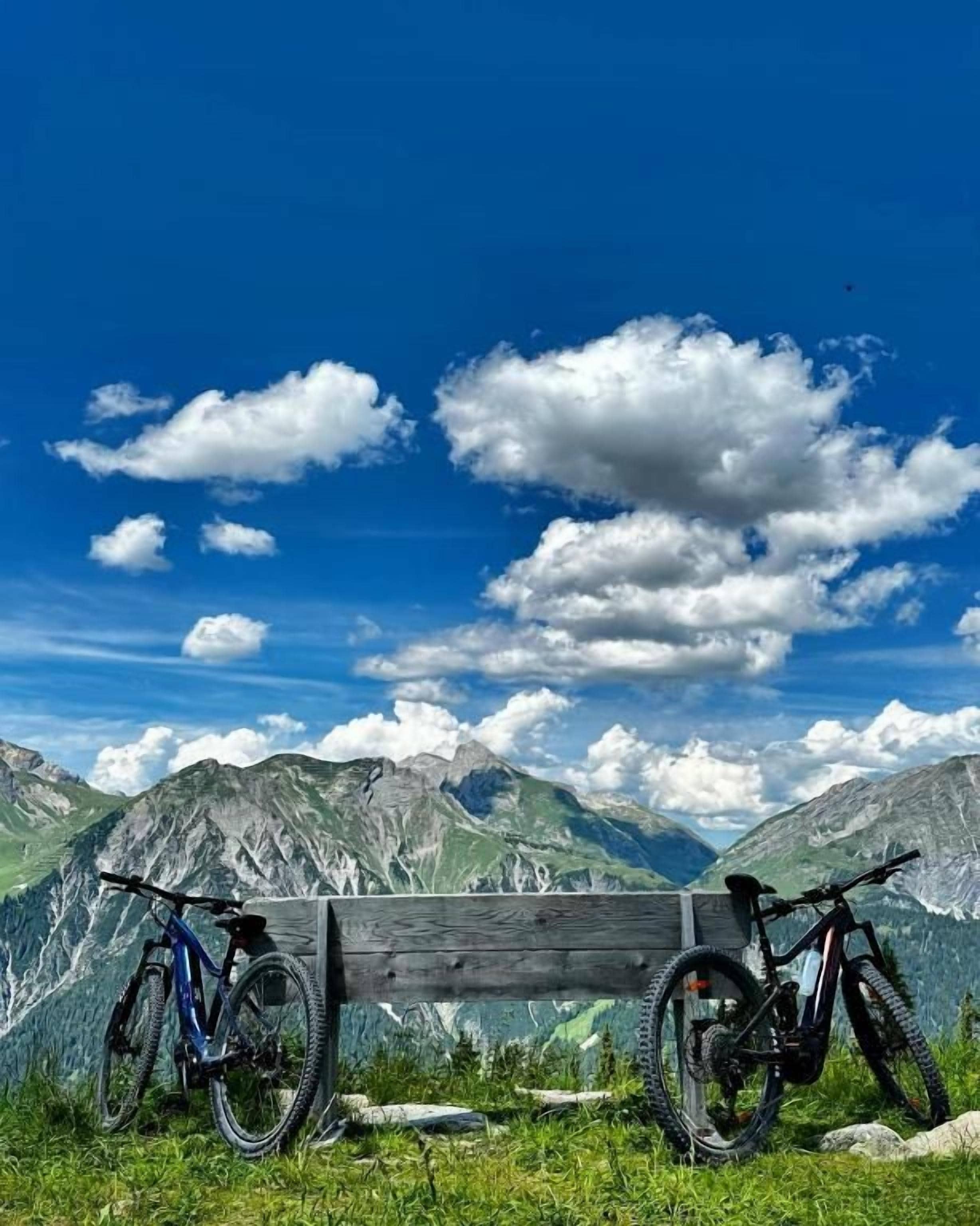 A bench with two bicycles in a mountainous landscape.