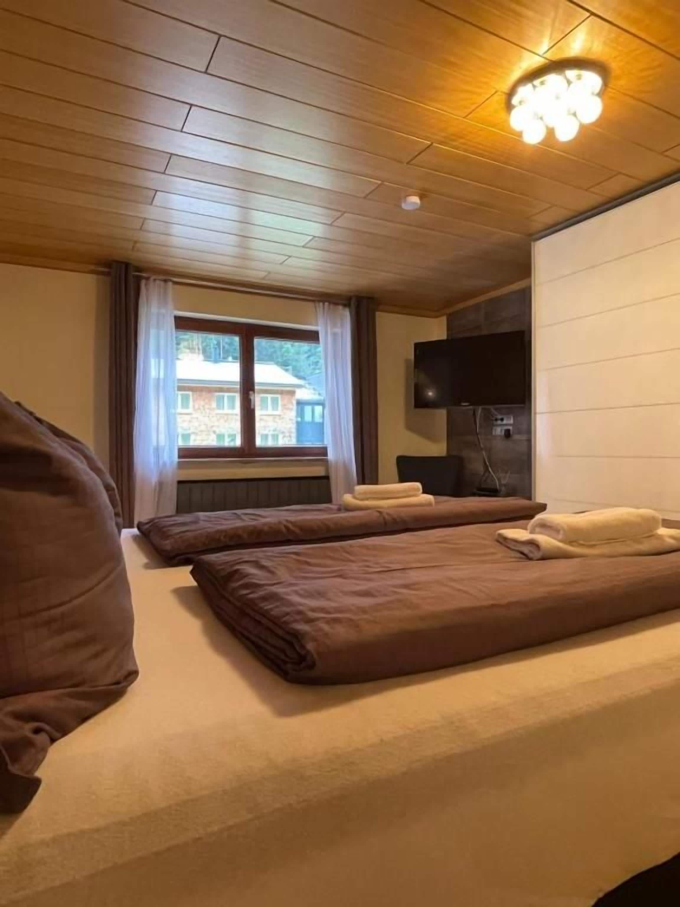 Een hotelkamer met twee bedden, een televisie en een raam met gordijnen.
