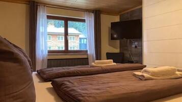 Een hotelkamer met twee bedden, een televisie en een raam met gordijnen.