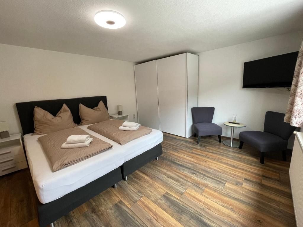 Una habitación de hotel con una cama, un armario, un televisor y una silla.