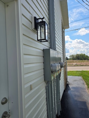 A house exterior with a white siding, a black lantern, and a grey electrical box.