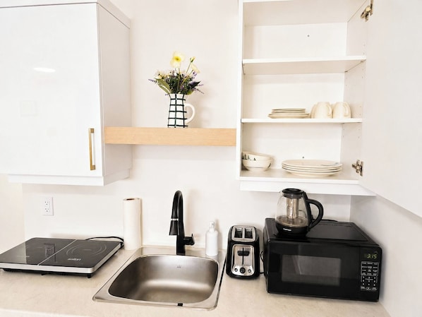 A kitchen with a sink, a toaster, a coffee maker, and a microwave.