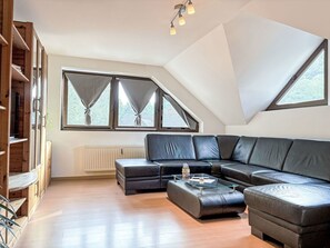 Ein modernes Wohnzimmer mit einem Ecksofa, einem Glastisch und einer integrierten Holzregallösung.