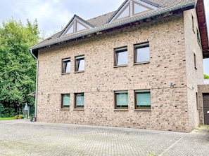 Um edifício de dois andares com fachada de tijolos, várias janelas e telhado inclinado.