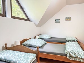 Ein Schlafsaalzimmer mit zwei hölzernen Etagenbetten, einem Fenster mit Blick auf Grünflächen und zwei kleinen gerahmten Bildern an der Wand.