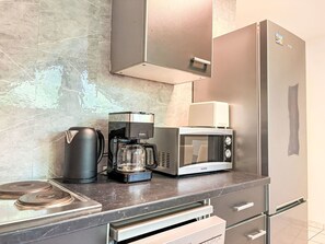Eine Küchenzeile mit Kaffeemaschine, Mikrowelle und Kühlschrank.