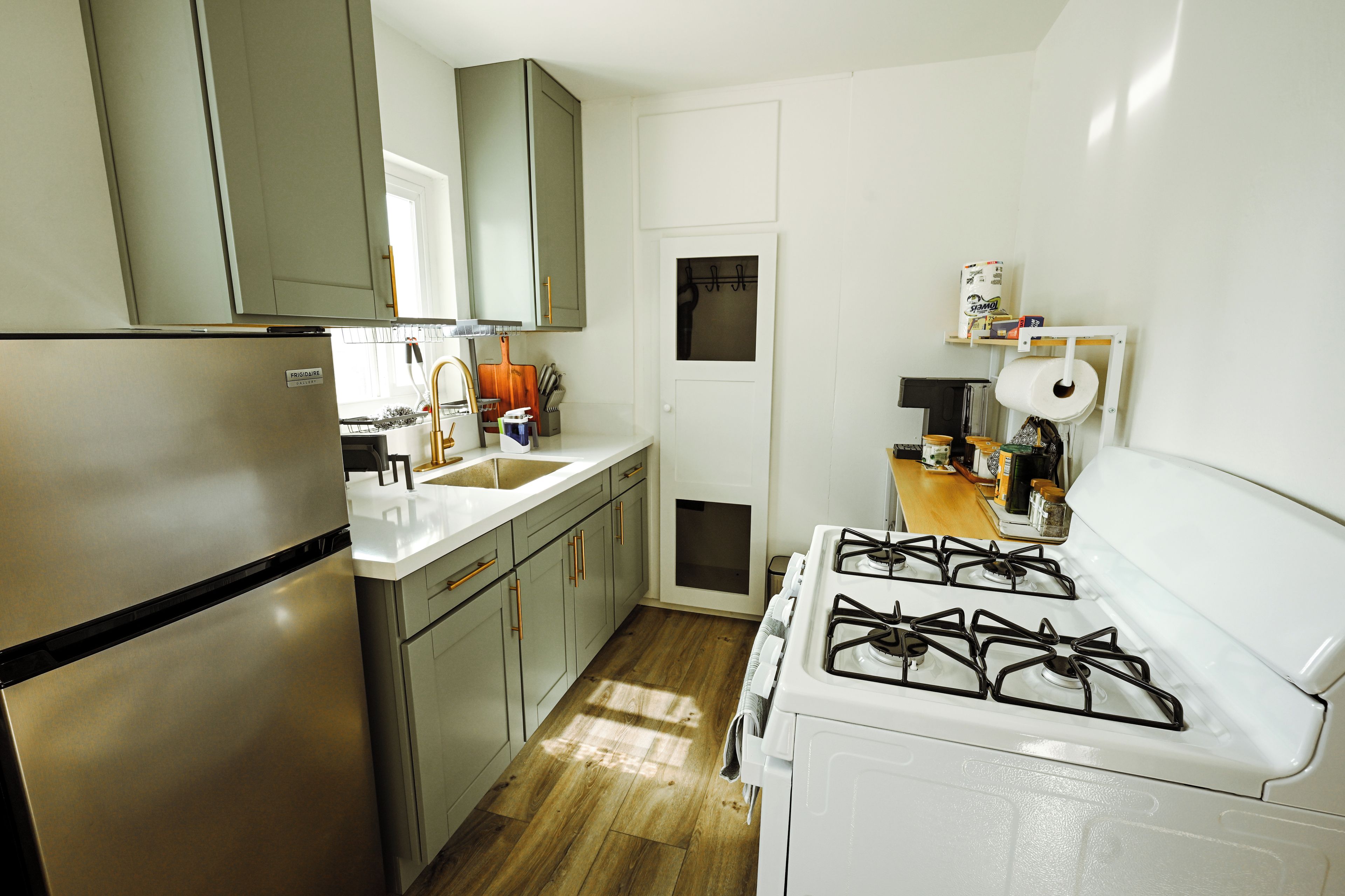A compact kitchen with a refrigerator, sink, stove, and cabinets.