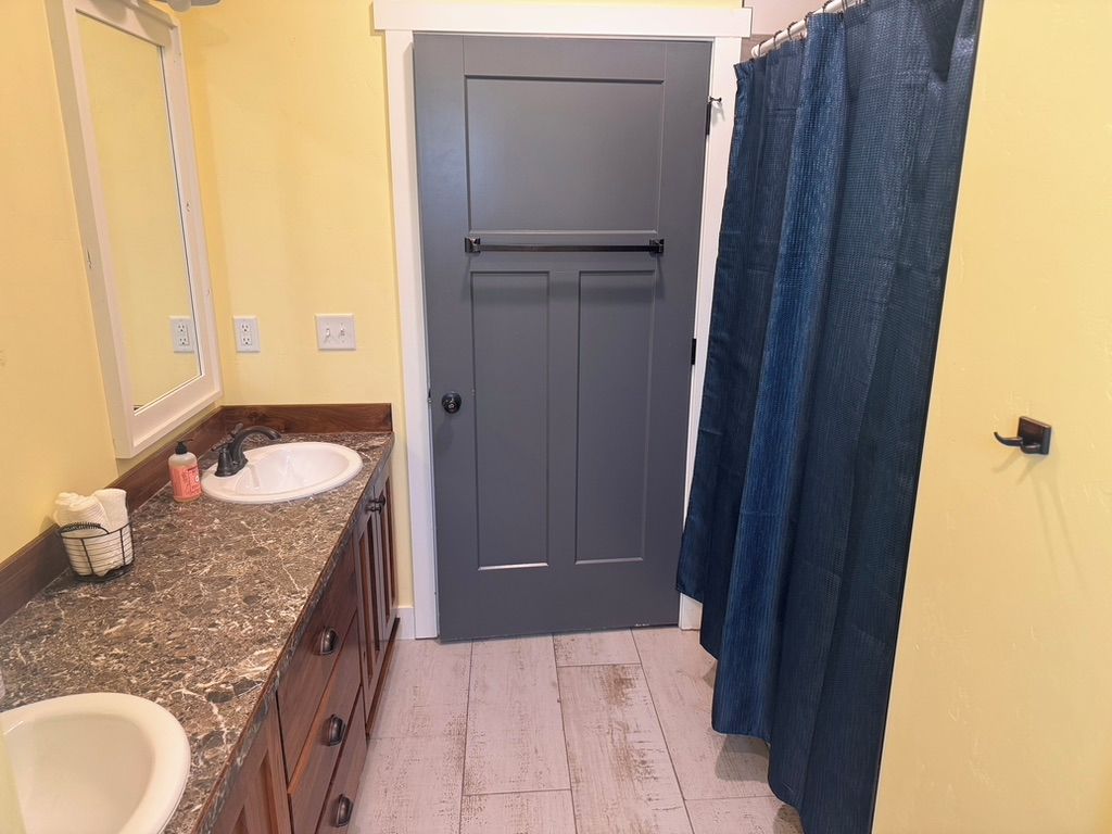 A bathroom with a double door, a sink, a mirror, and a shower curtain.