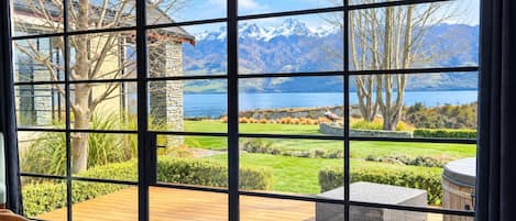 Habitació amb grans finestres que donen vista a un paisatge de muntanyes i un llac.
