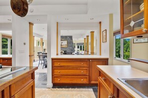 A modern kitchen with wooden cabinets, a central island, and a view into the dining area.