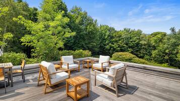 Une terrasse extérieure avec des meubles en bois et une vue sur une forêt.